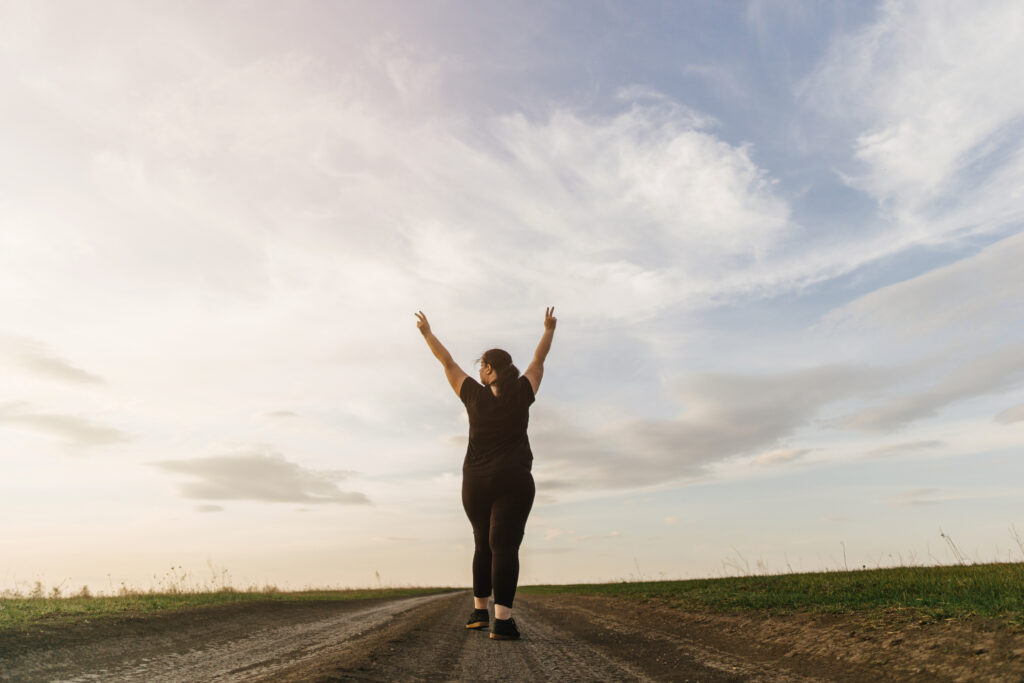 overweight woman celebrating rising hands to sky