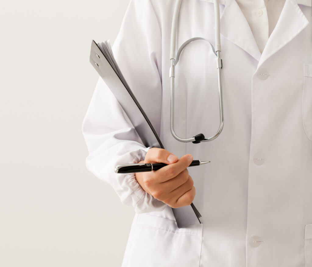 close up of doctor standing with pen and medical records in hand