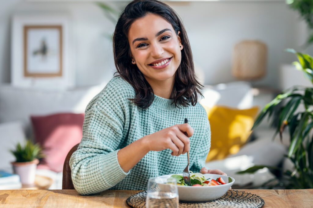 beautiful smiling woman eating healthy while looking at camera a